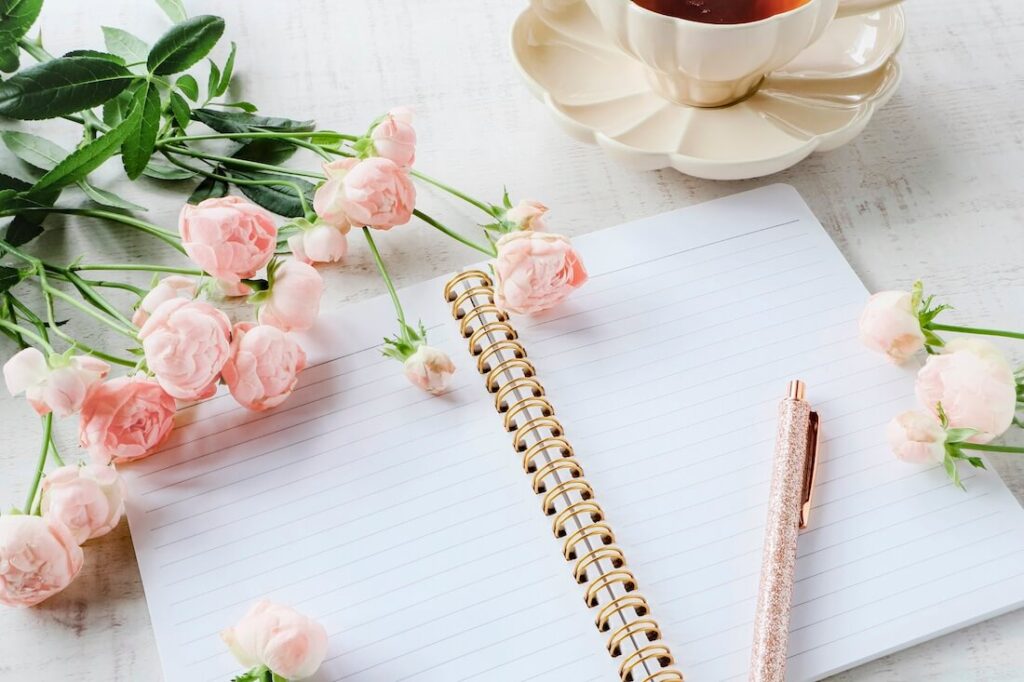ノートとペン、バラ、紅茶の写真