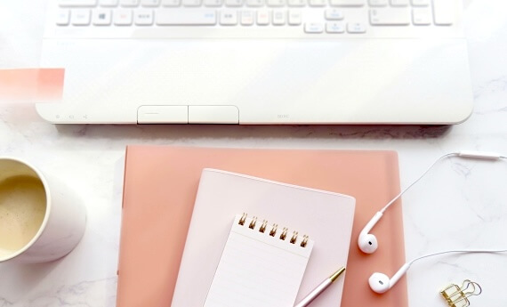 ノートパソコンとペン、メモ帳、イヤフォンの画像