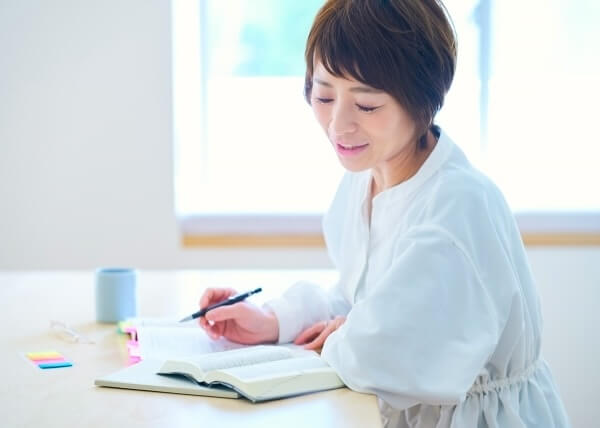 本を開いて勉強をしている女性の写真