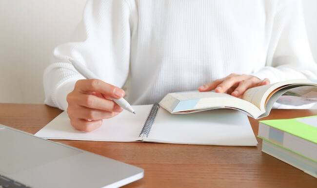 本とノートを開いて勉強している手元