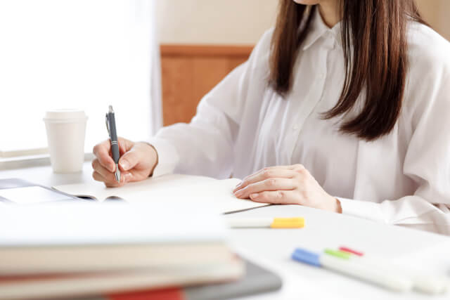 ノートを開いてペンを持つ女性の手元